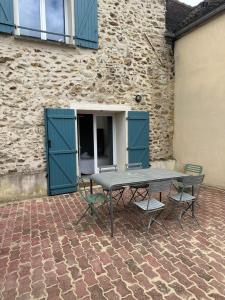 een picknicktafel en stoelen voor een gebouw bij La Maison des Ormes in Faremoutiers