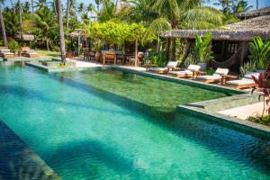 a swimming pool in a resort with chairs and trees at Bangalô Kauli Seadi Eco-Resort in São Miguel do Gostoso