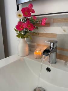 a sink with a vase of flowers and a candle at Les Hirondelles B in Le Crotoy