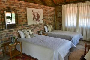 a bedroom with two beds and a brick wall at Kudusdrift Farmstay in Vaalwater