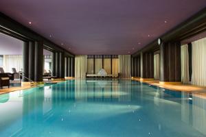 a large swimming pool with blue water in a building at La Réserve Genève Hotel & Spa in Geneva