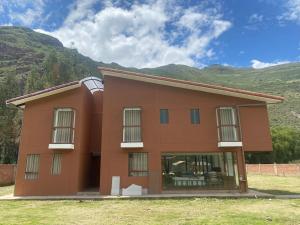 un bâtiment brun avec des montagnes en arrière-plan dans l'établissement Apus Paradise House Valle Sagrado, à Urubamba