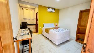 a bedroom with a white bed and a yellow wall at Porto Dolce Vita in Porto De Galinhas