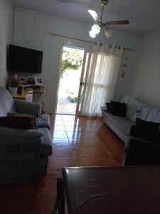 ein Wohnzimmer mit Sofas und einer Glasschiebetür in der Unterkunft Casa da Marina in Três Coroas