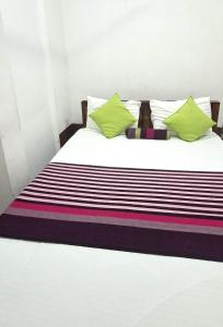 KalapaluwawaにあるNew Colombo Villageの黒と白の縞模様のシーツと緑の枕が置かれたベッド +18枚の写真