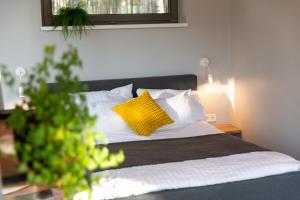 a bed with yellow and white pillows in a bedroom at Brīvdienu māja Empagi in Lādezers