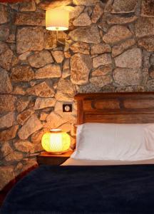 a bedroom with a stone wall with a bed and a lamp at Bergerie du Prunelli in Cauro
