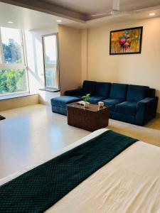 a living room with a blue couch and a table at Hotel Maira in Dehradun