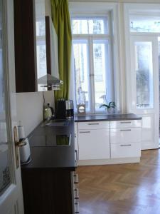 una cocina con armarios blancos, fregadero y ventanas en Apartment in City Center - MORASSI, en Karlovy Vary