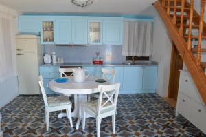 a kitchen with blue cabinets and a white table and chairs at Villa Blu Majestic beach villa in Halki +29 photos