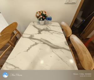 a marble table with two chairs and a vase with flowers at Chanhchua Apartment Quy Nhon in Quy Nhon
