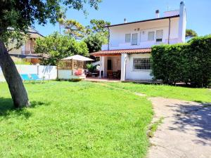 ein weißes Haus mit einem Baum im Hof in der Unterkunft Chill out Home Fregene Family Group Accomodation - 15 minuti da Fiumicino - Casa Vacanza Fregene vicino al mare in Fregene