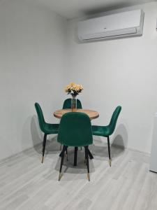 a table with green chairs and a vase with flowers at Box house M Andrijevica in Andrijevica