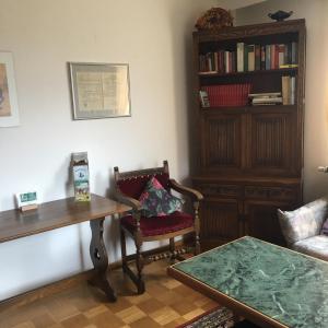 a living room with a table and a chair and a book shelf at Gästehaus-Eichwald in Neuenbürg