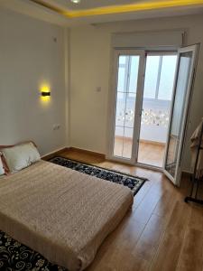 a bedroom with a bed and a large sliding glass door at Modern luxury apartment -f4- central Sétif in Sétif