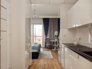a kitchen with white cabinets and a living room at Prymasa Tysiąclecia 83A City Center View By Perfect Apart in Warsaw