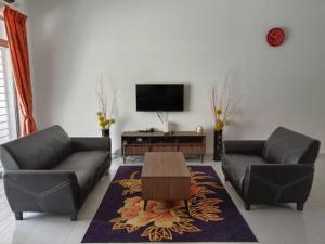a living room with two couches and a flat screen tv at The Diana Residence Muar in Muar