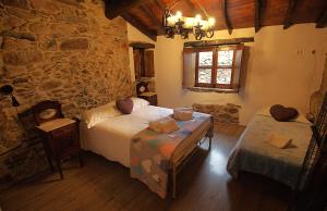 a bedroom with two beds and a stone wall at Talasnal Montanhas de Amor in Lousã +73 photos