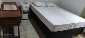 a bed in a room next to a table and a desk at Casa Moreira in Pirenópolis