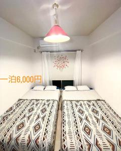 zwei Betten in einem kleinen Zimmer mit rosa Licht in der Unterkunft KT-HouSe Fukuoka ダブル in Sumiyoshi