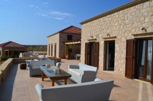 a patio with a bunch of chairs and a table at Villa Blu Majestic beach villa in Halki