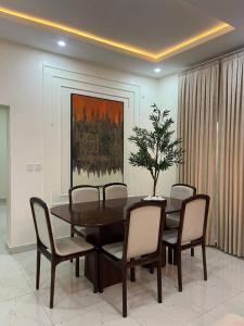 a dining room with a table and chairs and a painting at Nouveau Apartment in Abuja
