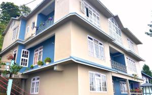 een gebouw met witte ramen en blauwe biezen bij Khangrila Nest Homestay in Sombāri