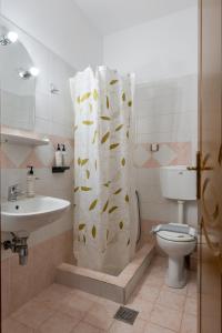 a bathroom with a shower curtain with a toilet and a sink at Mountain Hotels "Achais" in Planitéron
