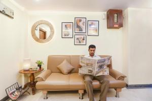 a man sitting on a couch reading a newspaper at FabHotel Shubhangan - Nr Bandra in Mumbai