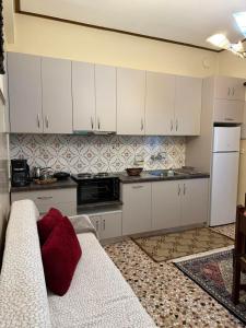 een keuken met witte kasten en een rood kussen op een bank bij Platanaki View in Pýli