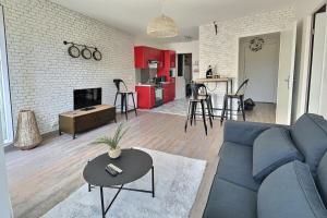 ein Wohnzimmer mit einer blauen Couch und einer Küche in der Unterkunft Le Manet, Lagny-sur-Marne in Lagny