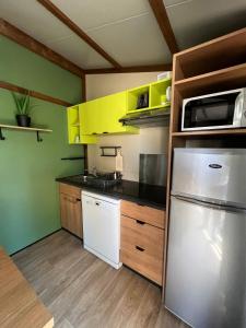a kitchen with yellow cabinets and a white refrigerator at 508 Mobilhome tout confort in La Teste-de-Buch