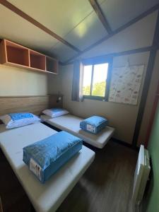 a room with three beds and a window at 508 Mobilhome tout confort in La Teste-de-Buch