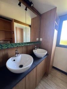 a bathroom with two sinks and a mirror at 508 Mobilhome tout confort in La Teste-de-Buch
