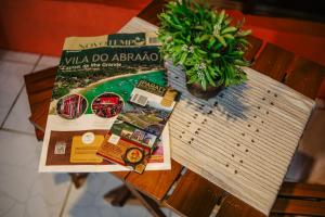Una mesa con un libro y una planta en maceta encima. en CASA DA ILHA INN and SPA Anexo2, en Angra dos Reis