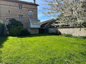 Un gran edificio de ladrillo con un patio con un árbol. en Le Magellan Coulommiers 77, en Coulommiers