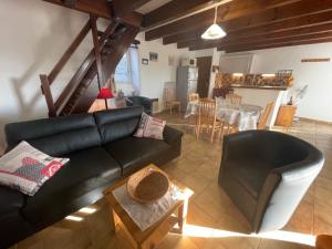 un salon avec un canapé noir et une table dans l'établissement Gîte Pierre Blanche - Village De Gîtes, à Rosières