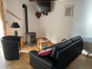 un salon avec un canapé noir et un poêle dans l'établissement Gîte Pierre Blanche - Village De Gîtes, à Rosières