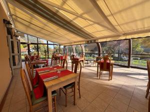 a restaurant with wooden tables and chairs and windows at Les Hirondelles in Orcines