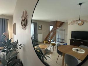 a living room with a table and a dining room with a mirror at Les Alois 10 min to Disneyland in Couilly-Pont-aux-Dames
