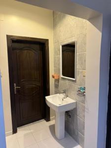 a bathroom with a sink and a brown door at اياد بامالك in Taif