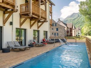 a house with a swimming pool with chairs and a deck at Mercure Peyragudes Loudenvielle Pyrénées in Loudenvielle