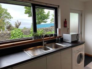 a kitchen with a sink and a microwave and a window at No 2 High Park Lodges in Orkney