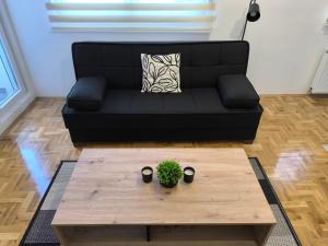 a living room with a black couch and a coffee table at Apartman Stefani in Pirot