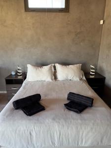 ein weißes Bett mit zwei schwarzen Handtüchern darauf in der Unterkunft Wine Studio with BBQ & pool in Las Heras