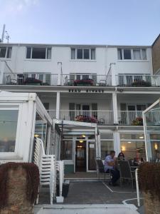 un grande edificio bianco con persone sedute fuori di Beau Rivage a St Brelade