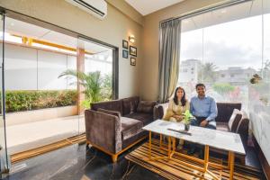 a man and a woman sitting in a living room at FabHotel Prime Rajmudra - Nr Butterfly Park - Hinjawadi in Pune