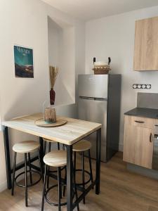 a kitchen with a table and stools and a refrigerator at Charmant T2 cosy à Mazamet in Mazamet