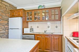 cocina con armarios de madera y nevera blanca en Vineyard Cottage BnB, en Gumeracha