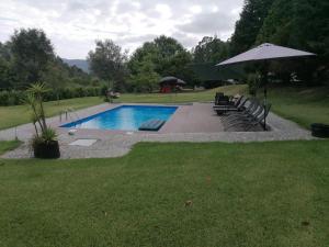 a swimming pool with chairs and an umbrella at Quinta da Costa in Monsul